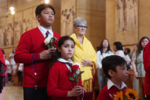 Catholic school students carry flowers to place in front of the Virgin Mary statue during the “One Mother, Many Peoples” Mass at the Cathedral of Our Lady of the Angels on Sept. 6, which celebrated the diverse cultures, organizations, and ethnic ministries in the Archdiocese of Los Angeles. (Reese Cuevas/Archdiocese of Los Angeles)