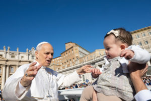 Pope Leo XIV greets a child as he rides the popemobile around St. Peter's Square at the Vatican before an audience for the Jubilee of Migrants and the Jubilee of the Missions Oct. 4, 2025. (CNS photo/Vatican Media)