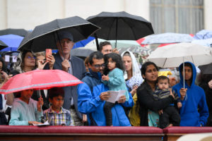 Pilgrims huddle under umbrellas as intermittent rain falls during Pope Leo XIV's Mass for the Jubilee of Migrants and the Jubilee of the Missions in St. Peter’s Square at the Vatican Oct. 5, 2025. (CNS photo/Vatican Media)