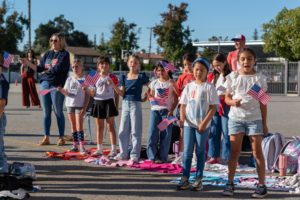 Students and parents wave flags and sing “God Bless America” during a Veterans Day event at Holy Angels School in Arcadia on Nov. 10. (Lawrence Lane)