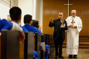 Msgr. Anthony Figueiredo, a priest in Assisi, Italy, speaks to inmates at LA Men’s Central Jail about the life of St. Carlo Acutis before Mass Oct. 20. At right is Deacon Fermin Lopez.  (Reese Cuevas)