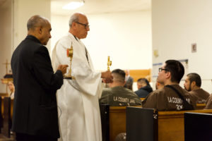 Msgr. Anthony Figueiredo, left, a priest in Assisi, Italy, speaks to inmates at LA Men’s Central Jail about the life of St. Carlo Acutis before Mass Oct. 20. At his right is Deacon Fermin Lopez.  (Reese Cuevas)