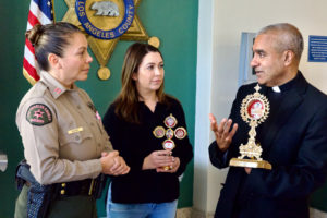 LA County Sheriff's Captain Cynthia Bearse, left, speaks with Msgr. Anthony Figueiredo, right, a priest in Assisi, Italy, during a tour of St. Carlo Acutis' relics to LA Men’s Central Jail on Oct. 20. (Reese Cuevas)