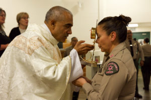 Msgr. Anthony Figueiredo holds the reliquary with St. Carlo Acutis’ pericardium to a sheriff's deputy's forehead during the saint's relic visit to LA Men’s Central Jail on Oct. 20. (Reese Cuevas)