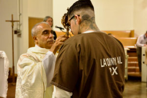 Msgr. Anthony Figueiredo blesses an inmate by holding the reliquary with St. Carlo Acutis’ pericardium to his forehead during the saint's relic visit to LA Men’s Central Jail on Oct. 20. (Reese Cuevas)