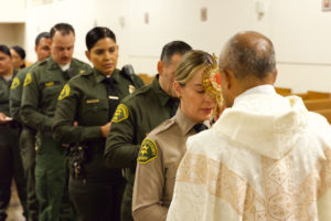 Msgr. Anthony Figueiredo holds the reliquary with St. Carlo Acutis’ pericardium to a sheriff's deputy's forehead during the saint's relic visit to LA Men’s Central Jail on Oct. 20. (Reese Cuevas)