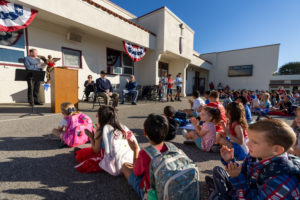 Father Kevin Rettig, left, the pastor at Holy Angels Church, offers remarks about Joe “Peppy” Sciarra during a Veterans Day event at Holy Angels School in Arcadia on Nov. 10. (Lawrence Lane)