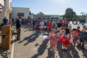 Joe “Peppy” Sciarra, a 100-year-old World War II veteran, left, stands with students while singing “God Bless America” during a Veterans Day event at Holy Angels School in Arcadia on Nov. 10. (Lawrence Lane)