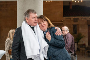 Msgr. Liam Kidney, pastor of the burned-down Corpus Christi Church in Pacific Palisades, hugs a parishioner following a Jan. 7 Mass on the one-year anniversary of the Palisades Fire at St. Monica Church in Santa Monica. (Elizabeth Friedrich)