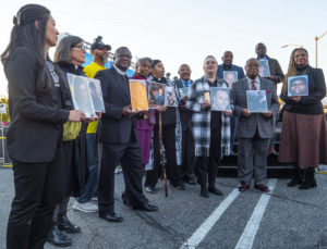 Fr. John Kyebasuuta, of St. Elizabeth of Hungary Catholic Church in Altadena,  joins other clergy members for a group picture on Wednesday, Jan. 7, 2026. Each member 
of the ecumenical group is holding a picture of a fire victim. Fr. Kyebasuuta is holding a picture of Victor Shaw. (Juanito Holandez Jr.)