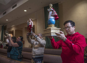 Jack Campano, right, his father Pete Campano, and sisters Tess Pena and Cristina Galestanian raise their Santo Niño statues during a Mass and Sinulog festival held at St. Philomena Church in Carson on Jan. 17. (Juanito Holandez Jr.)