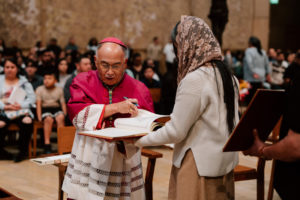 Auxiliary Bishop Brian Nunes signs a parish’s Book of the Elect during the Rite of Election ceremony at the Cathedral of Our Lady of the Angels on Feb. 15. (Peter Lobato)