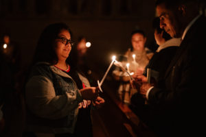 Attendees have their flames lit by the Paschal candle during the Easter Vigil at the Cathedral of Our Lady of the Angels on April 4. (Peter Lobato)