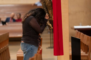A woman prays at the feet of Jesus on the cross during the Good Friday liturgy at the Cathedral of Our Lady of the Angels on April 3. (Reese Cuevas)
