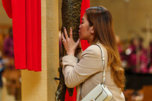 A woman kisses the feet of Jesus on the cross during the Good Friday liturgy at the Cathedral of Our Lady of the Angels on April 3. (Reese Cuevas)