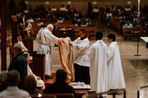 Archbishop José H. Gomez removes his vestments as he prepares for the Washing of the Feet during the Mass of the Lord's Supper at the Cathedral of Our Lady of the Angels on April 2. (Peter Lobato)