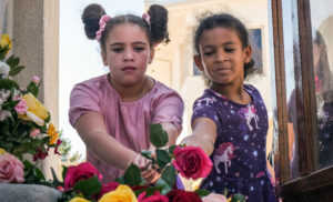Two young girls lay flowers at the feet of the Virgin Mary statue during a May crowning event at Sacred Heart Church in Lancaster. (Katie Trejo)