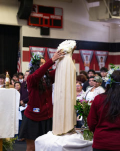 Olivia Udabe, a student at St. Pius X-St. Matthias Academy in Downey, crowns the Virgin Mary statue during a May crowning ceremony at the school. (St. Pius X-St. Matthias Academy)