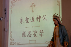 Chinese characters are displayed on a screen during Father Shengda (Martin) Zhu's first Mass at his home parish of St. Thomas Aquinas Church in Monterey Park on May 31. (John Rueda)
