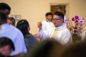 Father Shengda (Martin) Zhu offers holy Communion during his first Mass at his home parish of St. Thomas Aquinas Church in Monterey Park on May 31. (John Rueda)