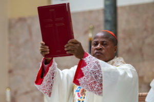 Cardinal Peter Ebere Okpaleke of Ekwulobia, Nigeria, holds up the Book of Gospels during a special May 31 Mass at St. Eugene Church in South LA. The cardinal visited LA as part of a tour visiting Nigerian Catholics living in the U.S. (Michael Goulding)