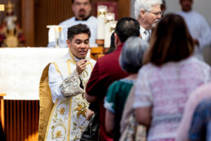 Father Jerick Alenton offers holy Communion during his first Mass at his home parish of St. Clare of Assisi Church in Santa Clarita on May 31. (Joe Garcia III)
