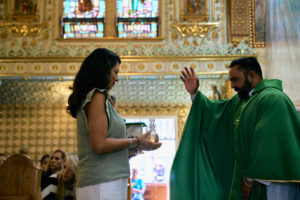 Venezuelan priest Father Alexander Hernandez, CSsR, accepts the gifts during a Mass for victims of the Venezuela earthquakes Sunday, June 28, at Nuestra Señora de Guadalupe Church in East LA. (John Geronilla)