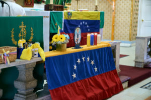 Parishioners add a Venezuelan flag to the altar during a special Mass at Nuestra Señora de Guadalupe Church in East LA on Sunday, June 28, to pray for victims of the Venezuela earthquakes. (John Geronilla)